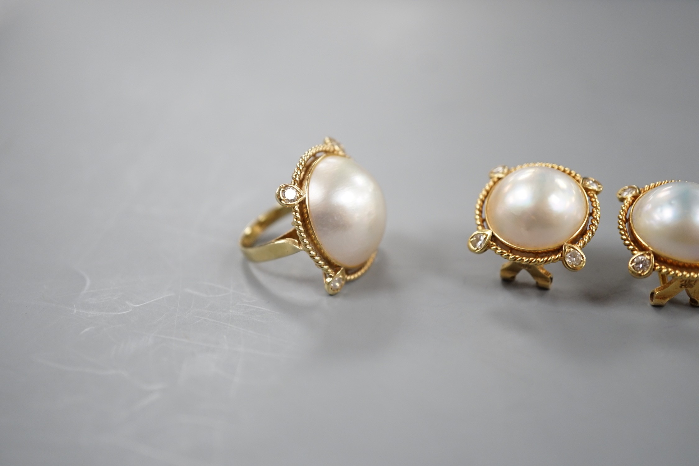 A yellow metal, mabe pearl and four stone diamond chip set dress ring, size H and a pair of similar earrings stamped 585 14k, gross weight 17.1 grams.